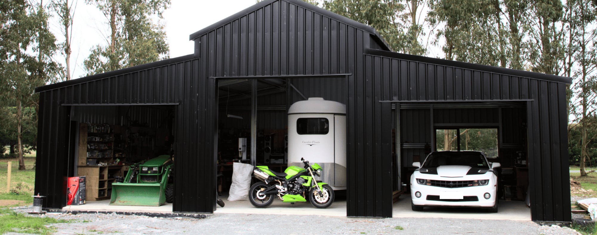 Wide Span Sheds exterior view of a shed containing horse float, motorbike and other vehicles